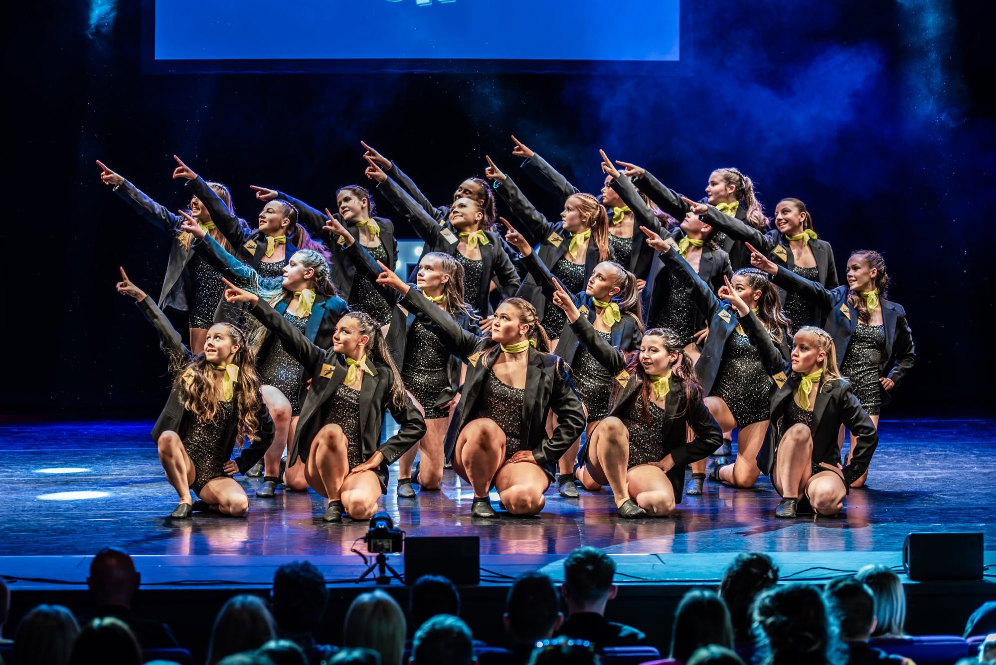 Dance troupe performing on stage in matching black and gold costumes