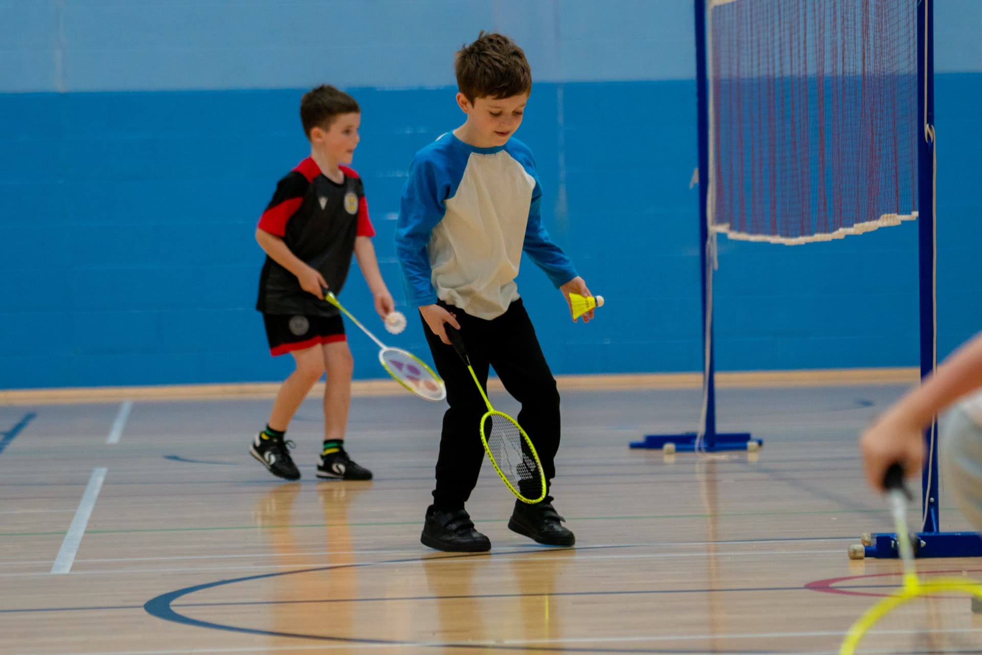 Two boys practising badminton beside the net