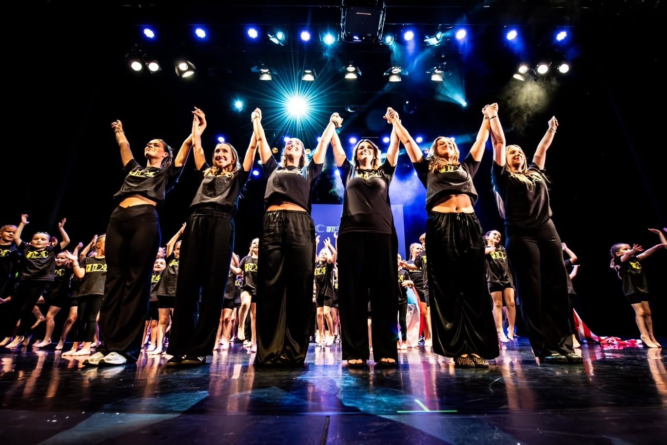 Dance troupe taking a bow on stage under blue lights